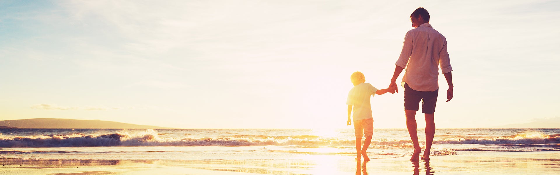 niño y padre caminando hacia el mar