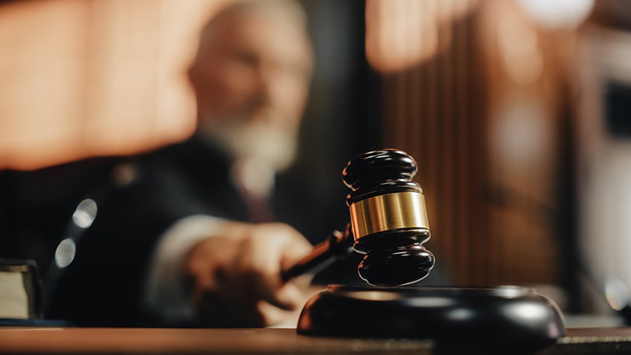 Un juez sosteniendo un mazo en un tribunal, listo para golpear, con un fondo difuminado